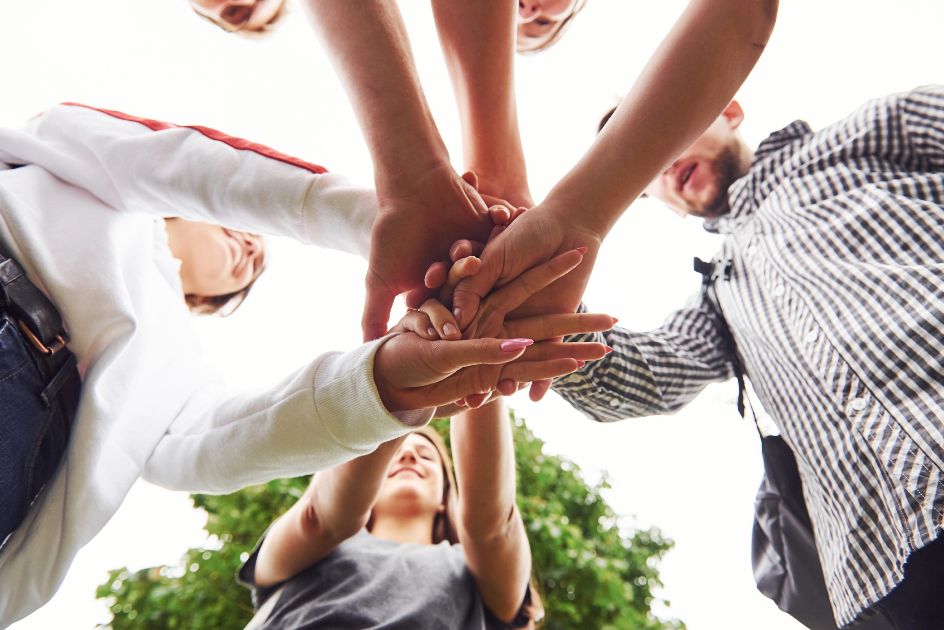 Manos unidos al centro en celebración. Trabajo de equipo.